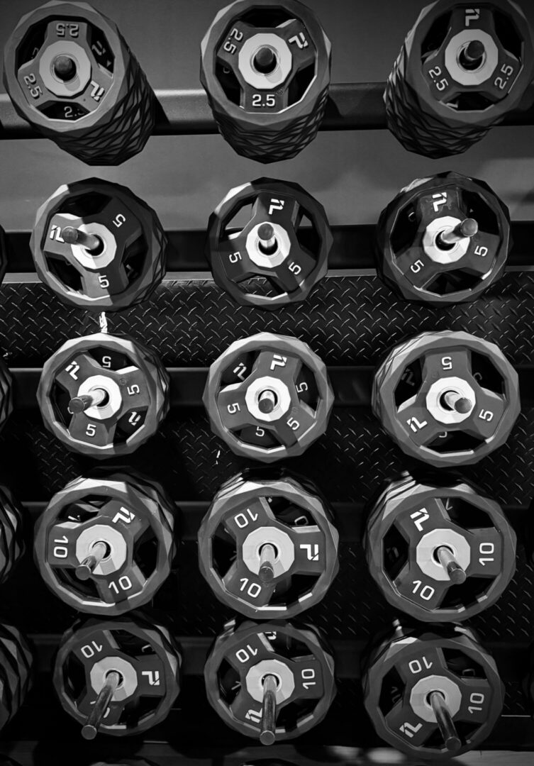 Black and white image of dumbbells arranged on a rack in a gym.