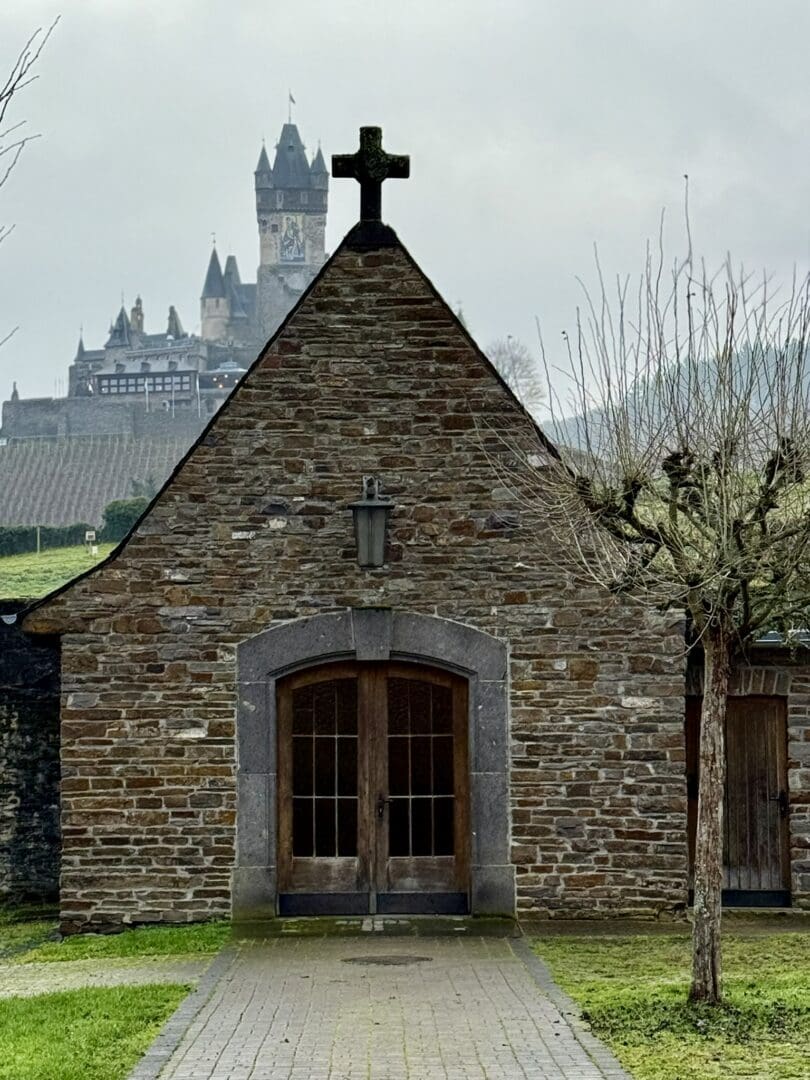 Stone chapel gable with cross and distant castle