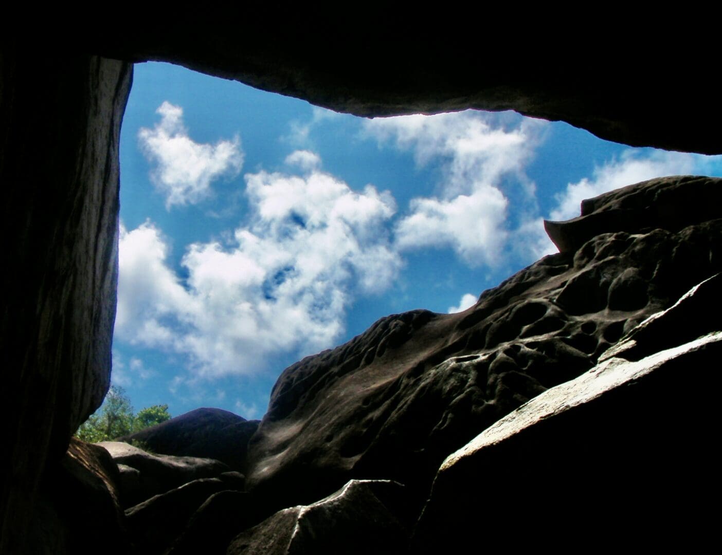 View of blue sky through rocky cave opening.